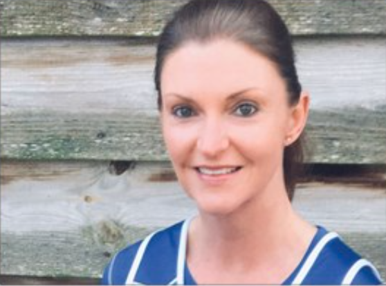 female smiling with wooden panels behind her