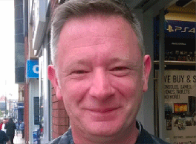 male smiling with shop fronts behind him