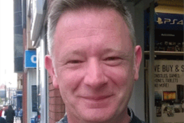 male smiling with shop fronts behind him