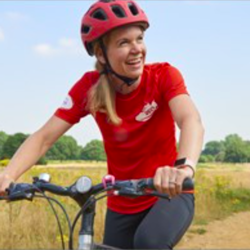 female cycling past a field of golden crops