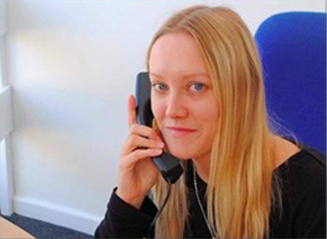female smiling holding a landline phone to her ear