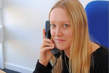 female smiling holding a landline phone to her ear