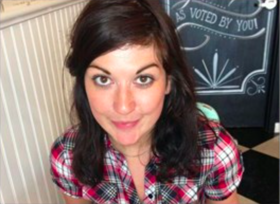 female wearing a check shirt looking up to the camera and smiling 