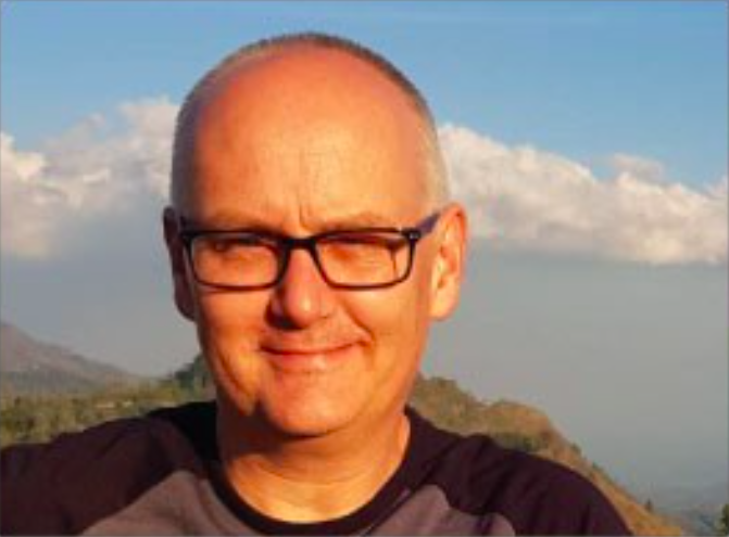 male smiling with a Rocky Mountain behind him