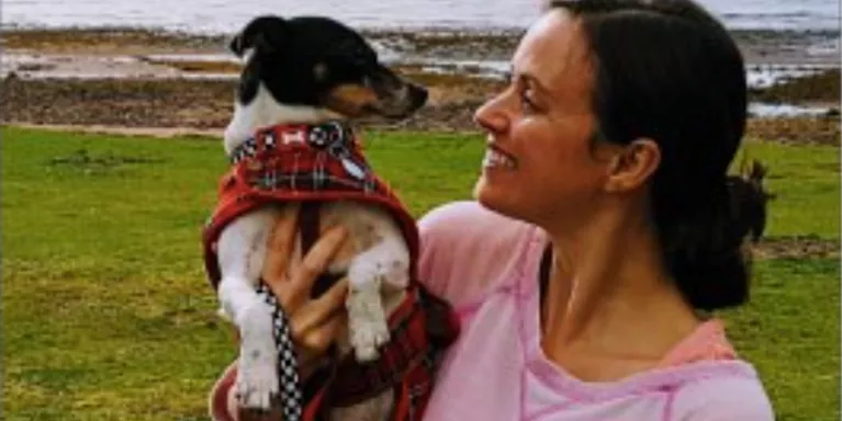 female holding small dog, smiling at it