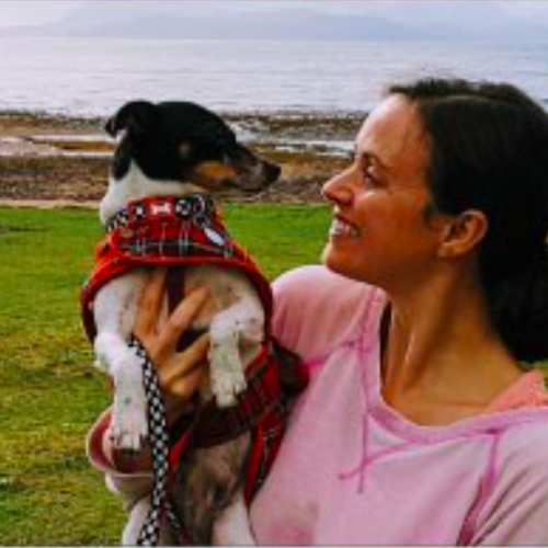 female holding small dog, smiling at it