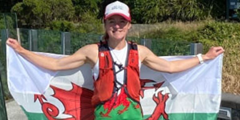 Menna in her running gear holding up a flag of Wales