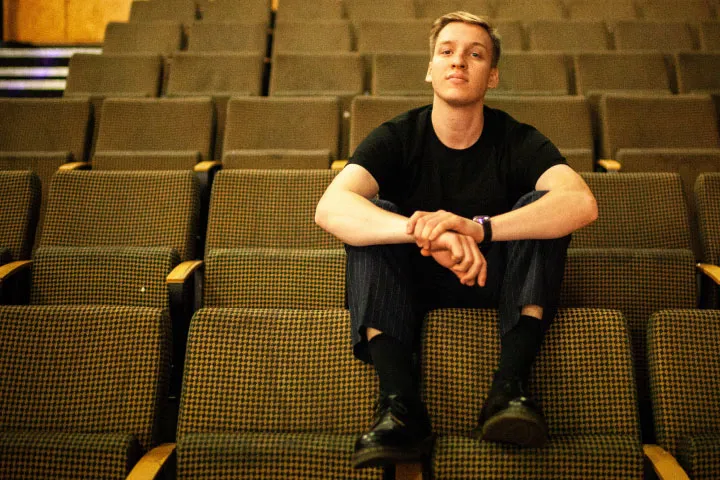 George Ezra sitting on back of chair at concert venue