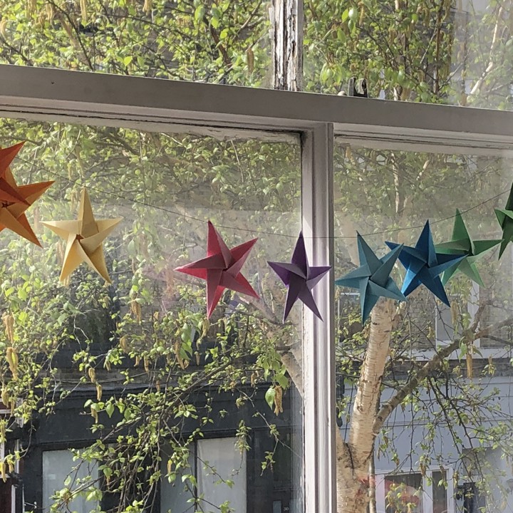 image showing rainbow bunting hanging in a window made from origami stars
