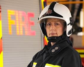 Female firefighter wearing a helmet in front of the word "Fire"