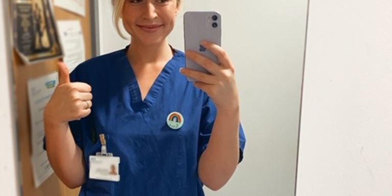 Photograph of nurse Jess in scrubs taking selfie 
