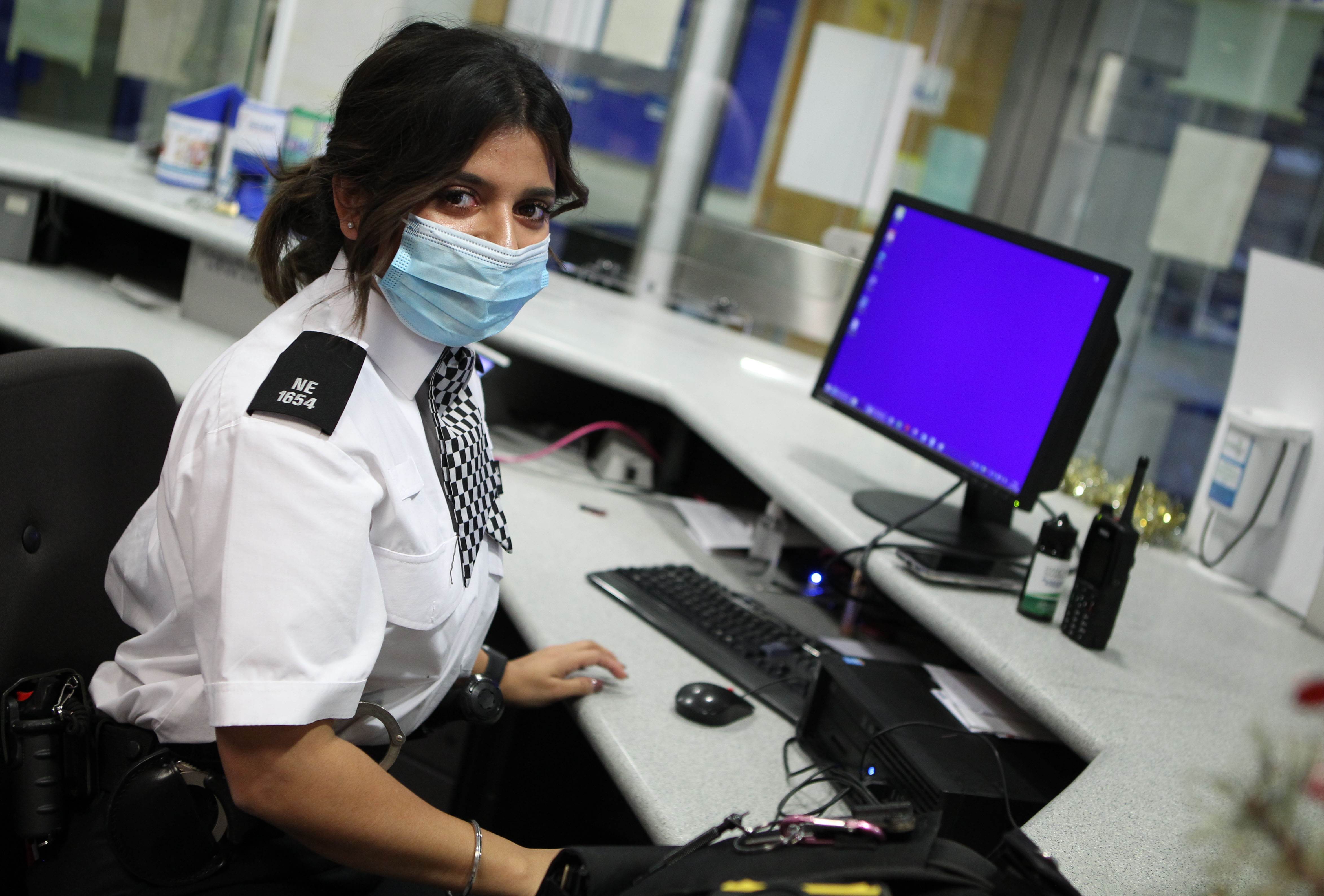 Metropolitan police officer sat at desk looking at camera