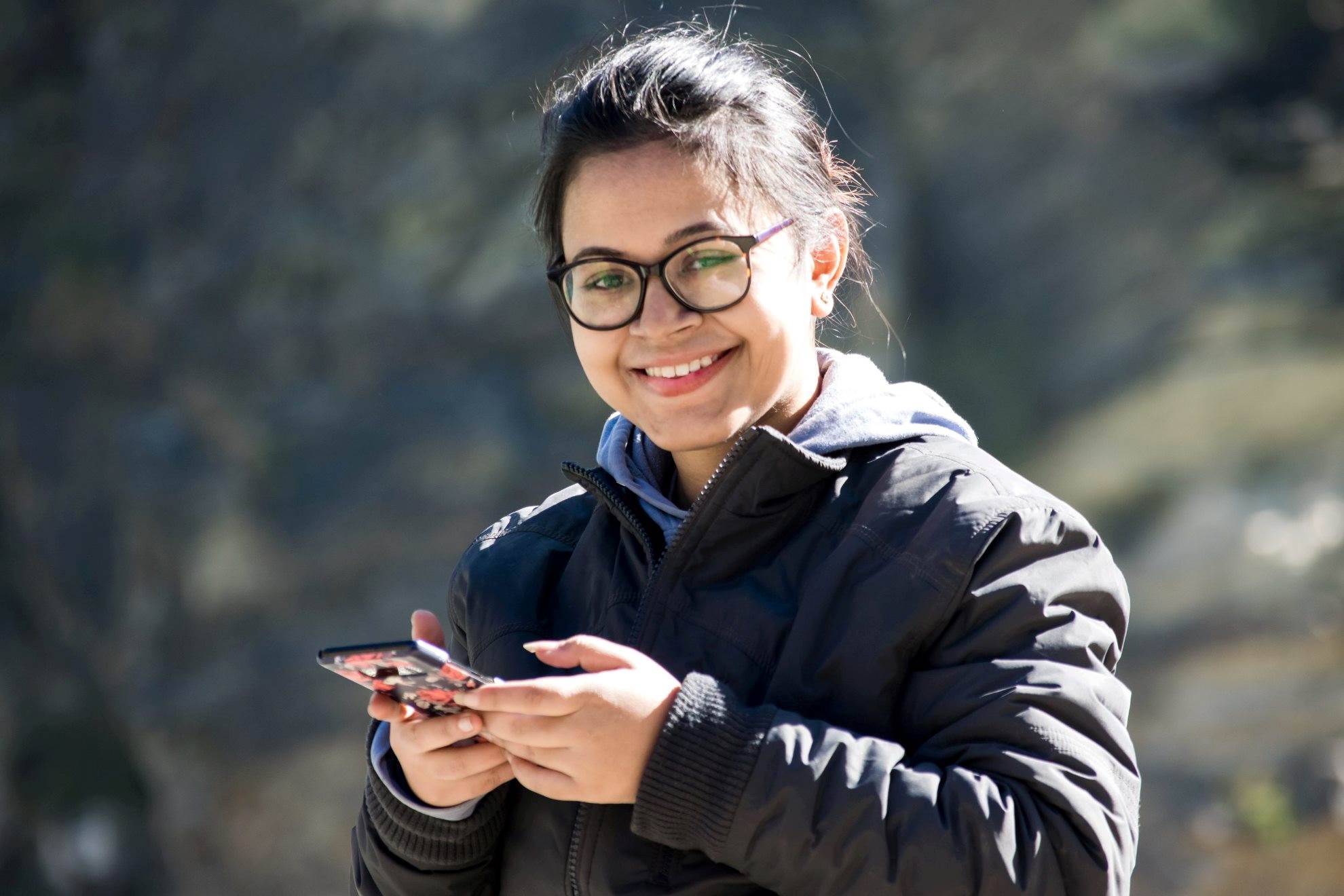 Woman with glasses on smartphone smiling at camera