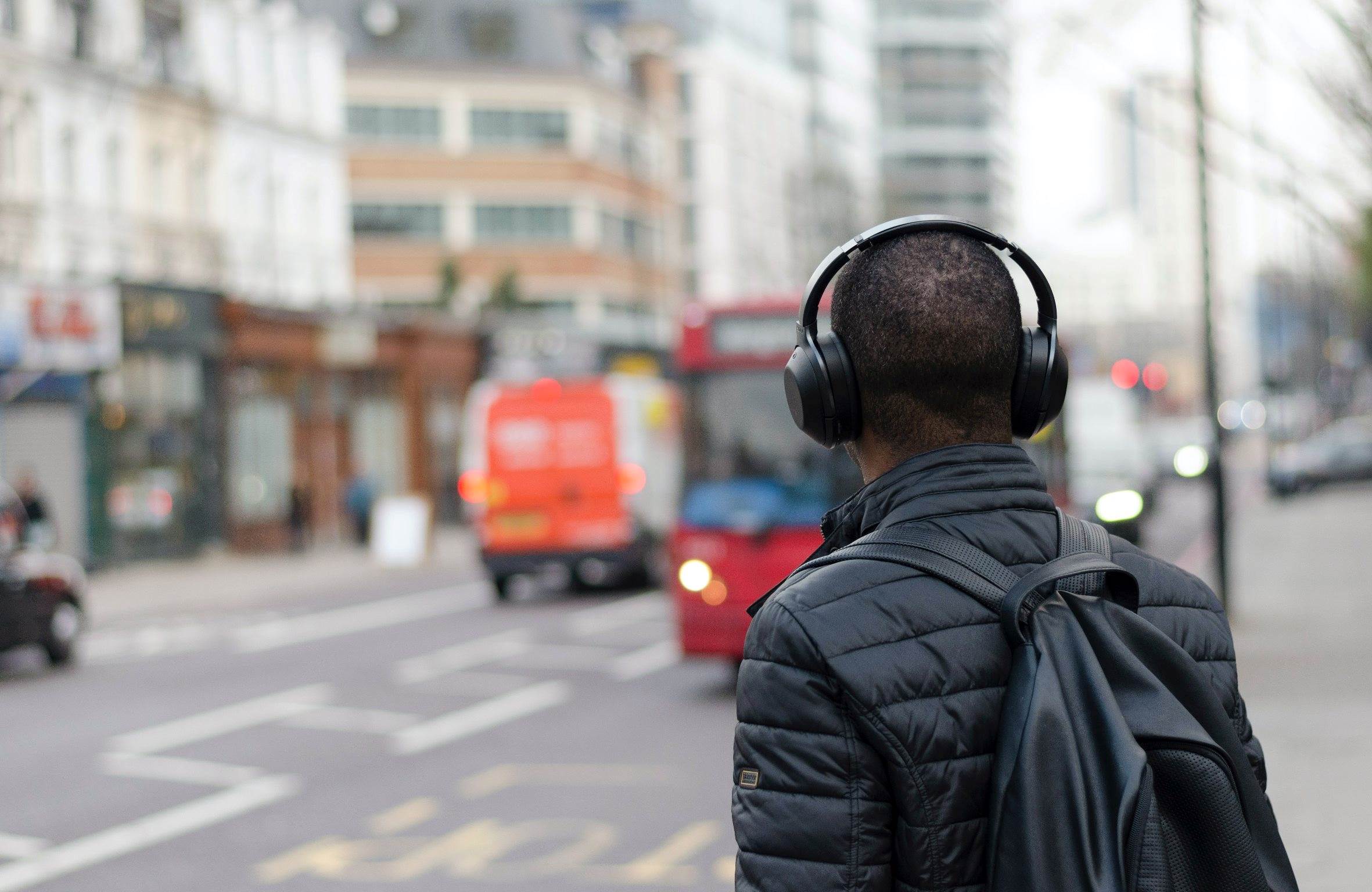 Person with headphones at a bus stop