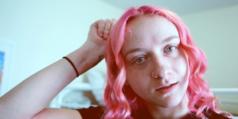 Person with pink hair and a wrist tattoo