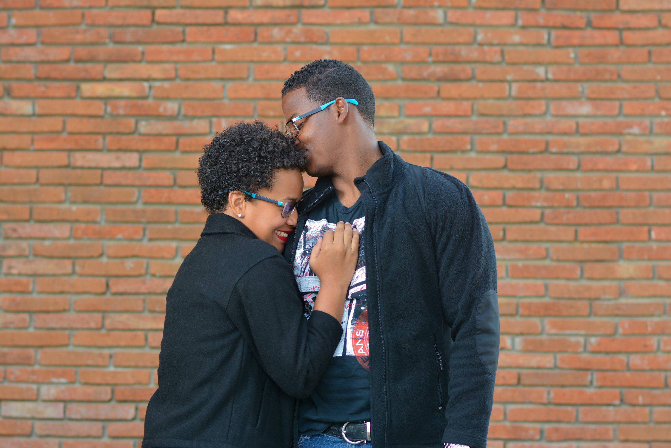 Two people hugging in front of a wall