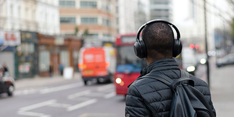 Person with headphones at a bus stop