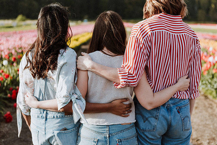 Three people facing away with arms round each other