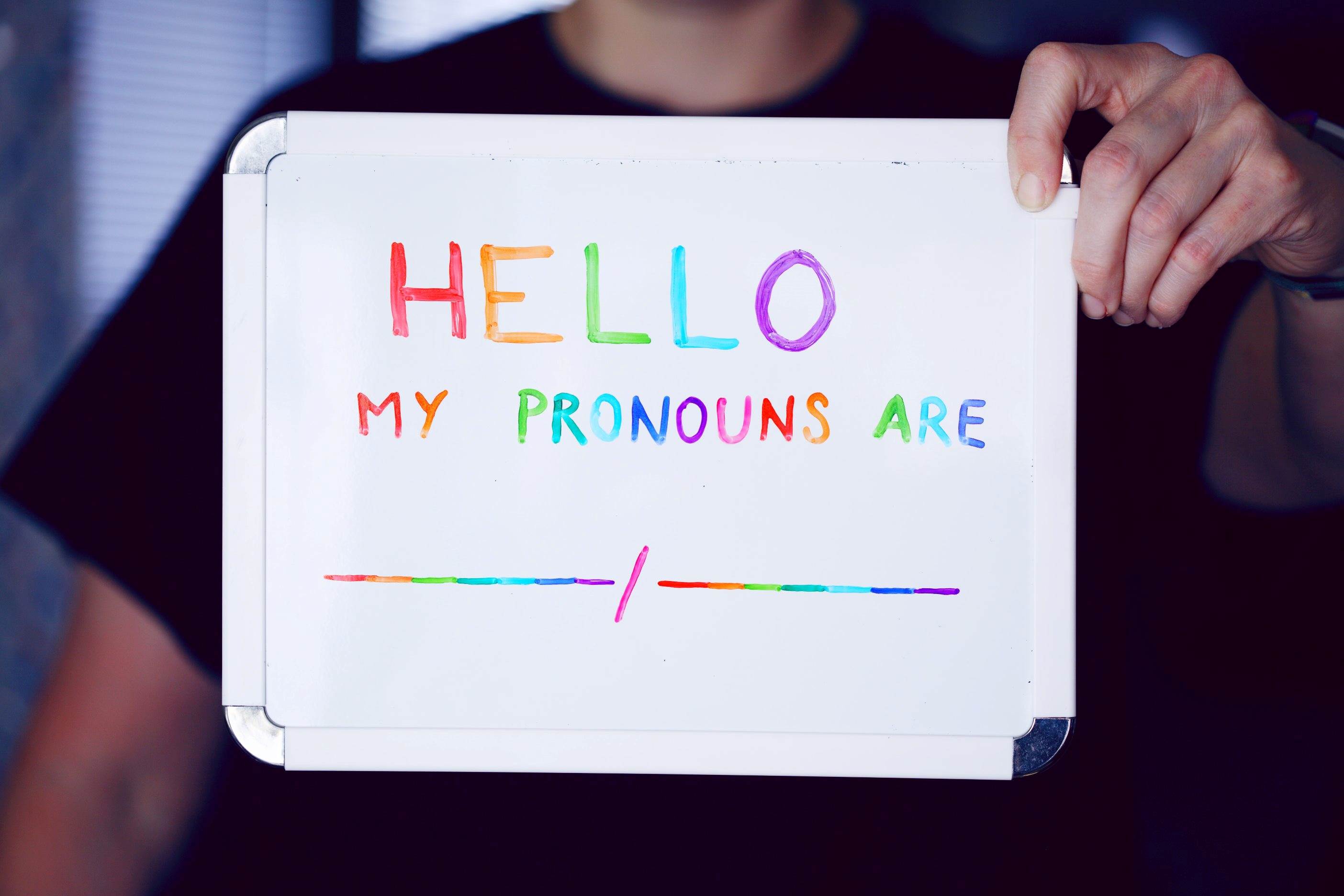 Hello my pronouns are... sign being held up by a person