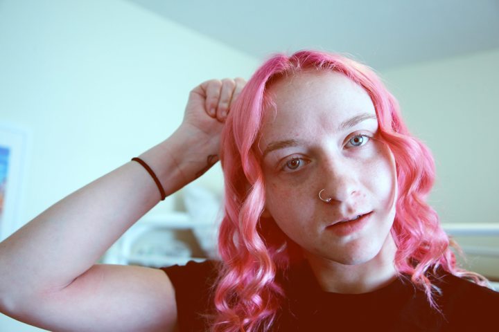 Person with pink hair and a wrist tattoo