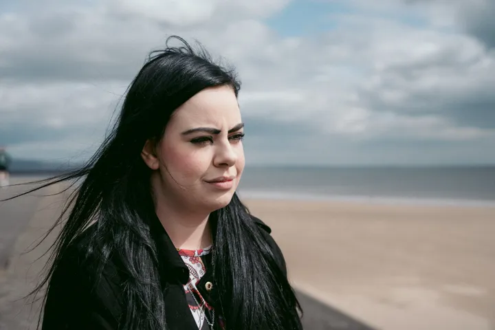 White woman with black hair looking to the side, with the beach in the background. White woman with black hair looking to the side, with the beach in the background.
