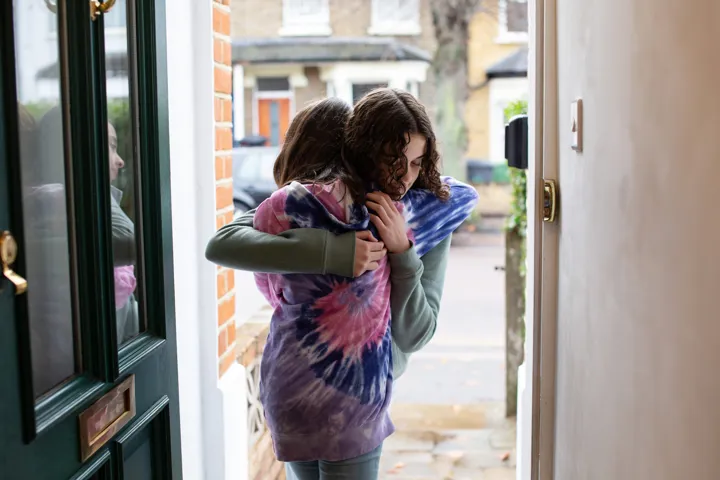 2 young people hugging at front door 2 young people hugging at front door