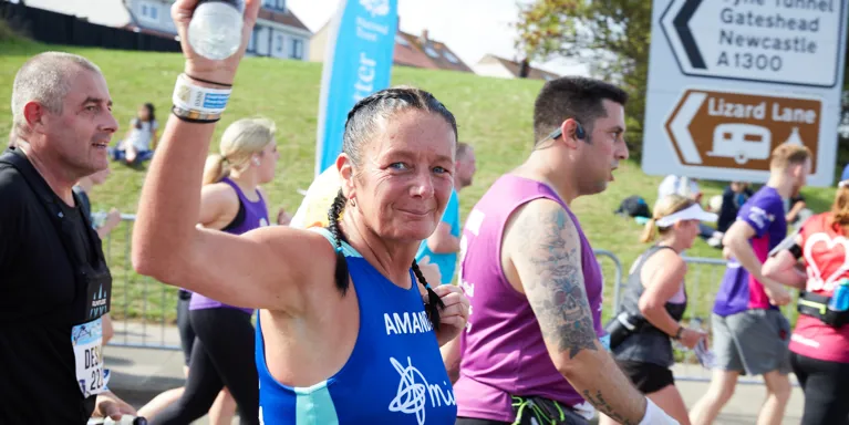 woman running in race wearing Mind top and holding water bottle woman running in race wearing Mind top and holding water bottle