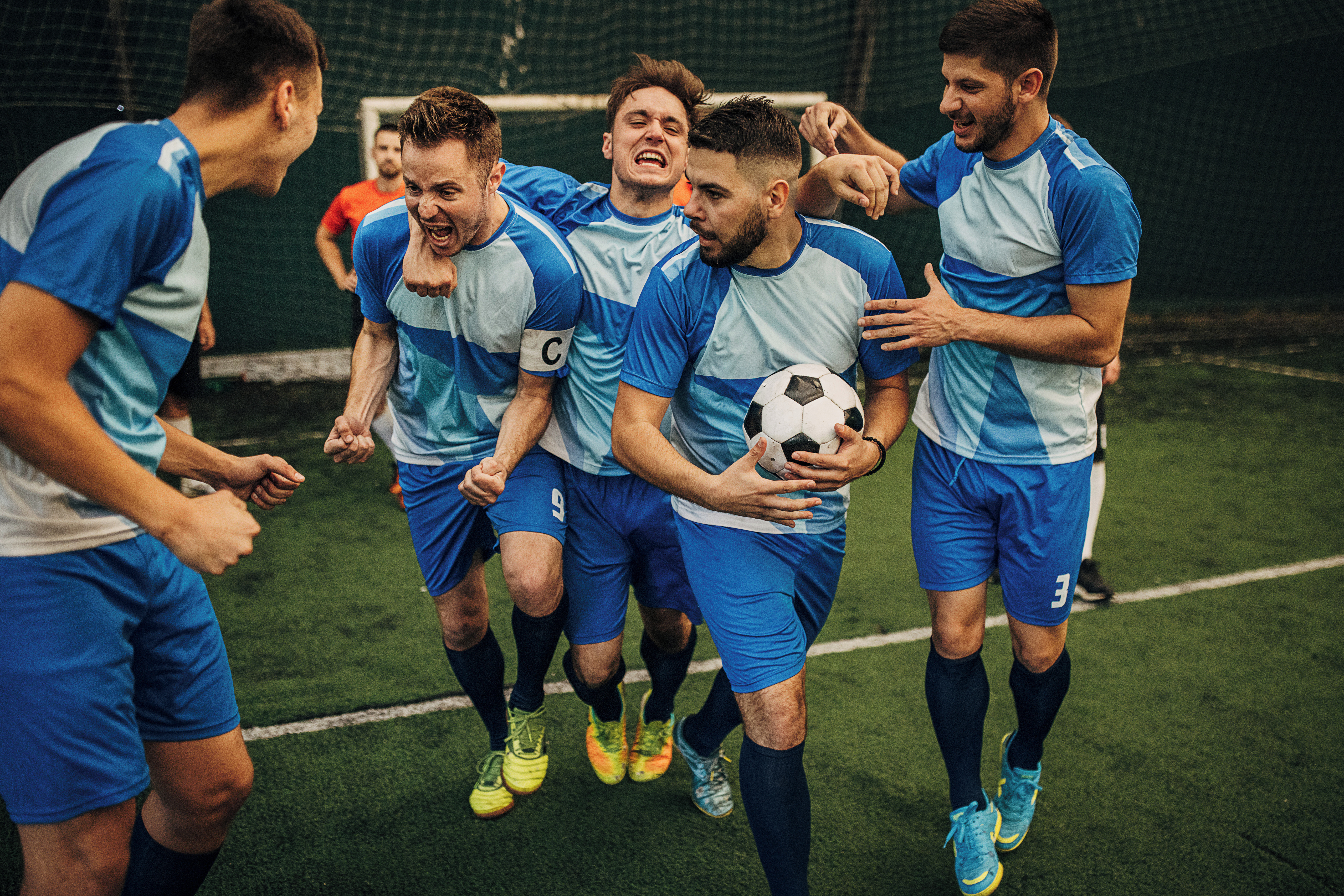a group of men huddled together after scoring a goal in football