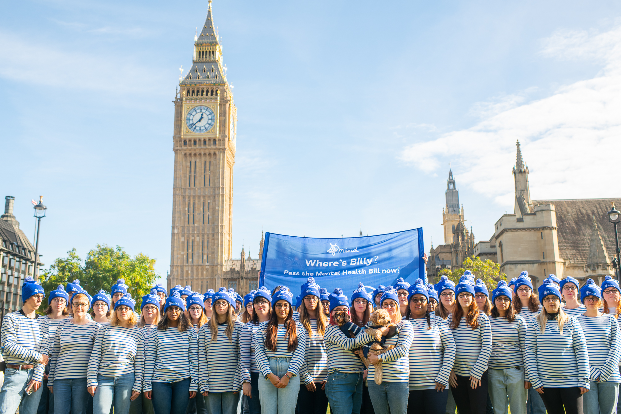 Campaigners dressed up in stripey shirts and blue bobble hats (looking like Where's Wally?). They're in front of the houses of parliament and holding a banner that says 'where's billy? pass the mental health bill now!'