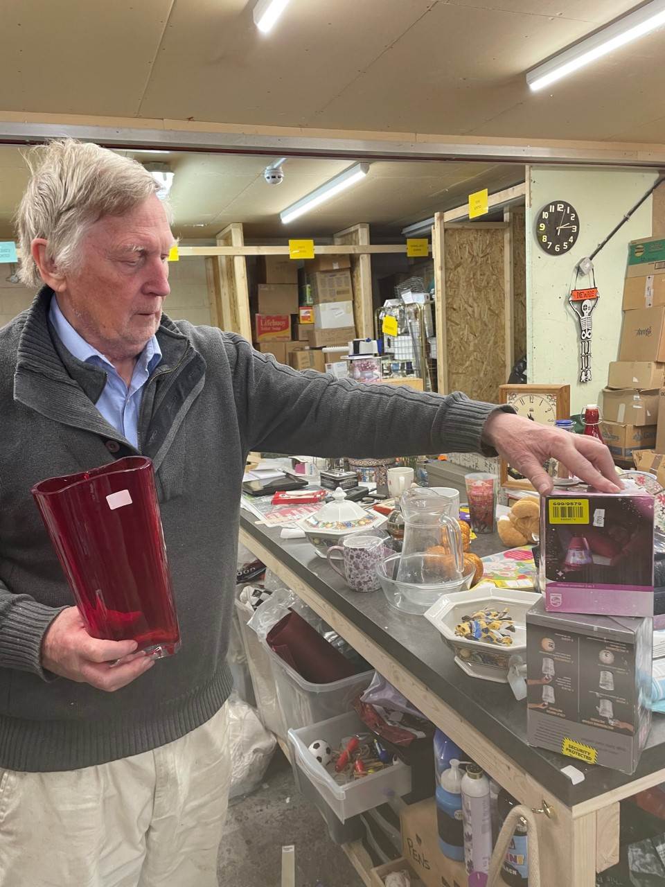 Man holding donations at a charity shop.