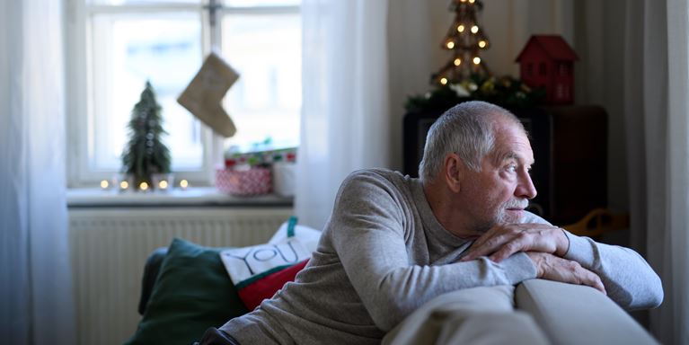 Man looking away from camera out window with Christmas decorations behind him