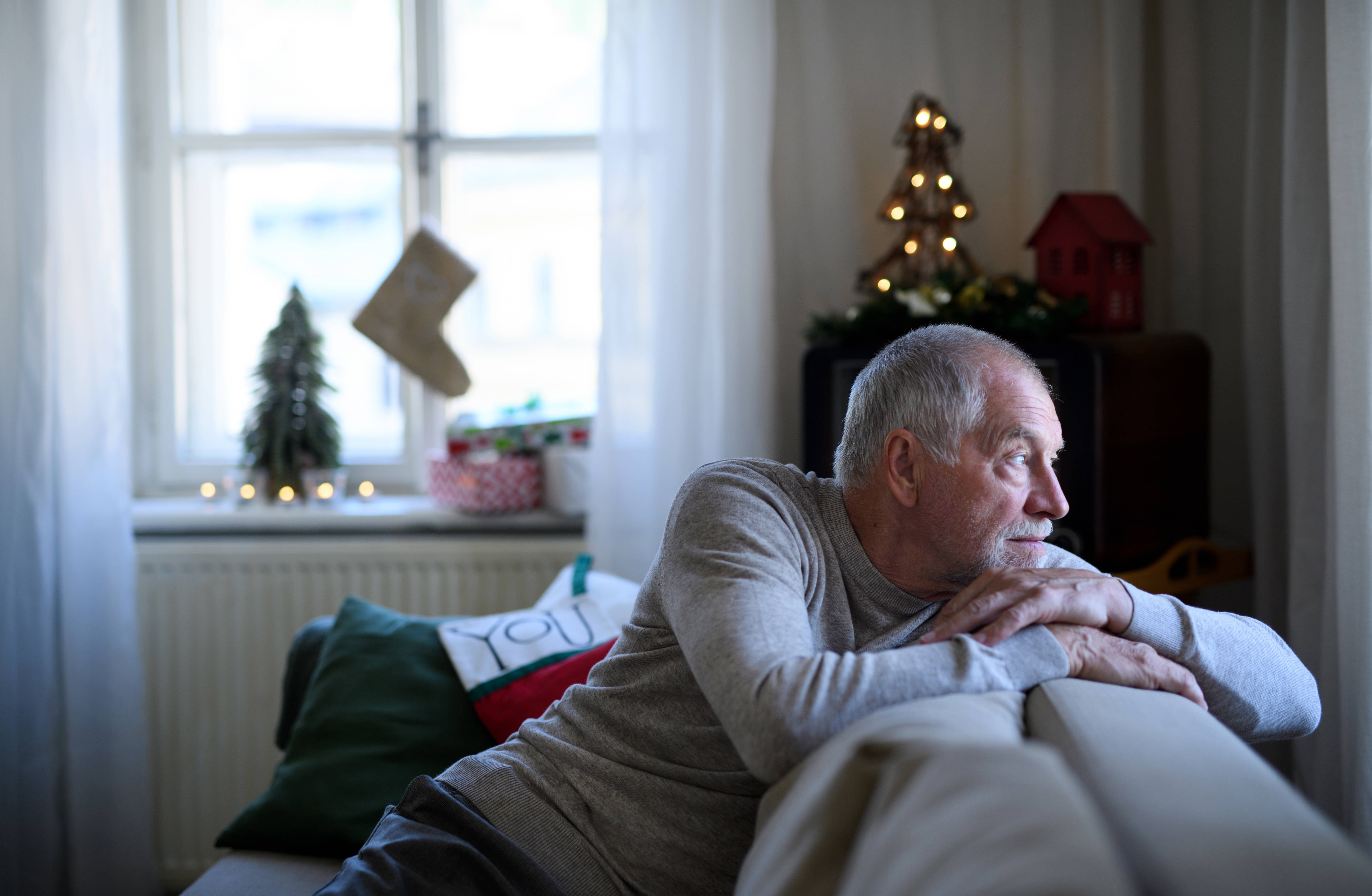 Man looking away from camera out window with Christmas decorations behind him